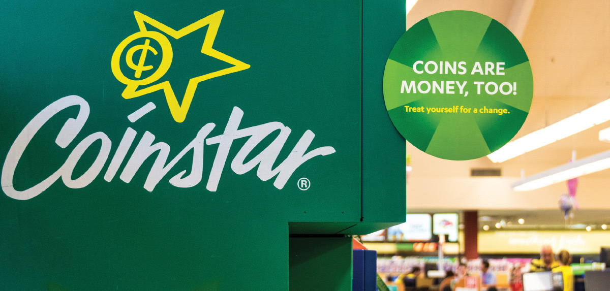 A green Coinstar machine with a circular sign reading "COINS ARE MONEY, TOO! Treat yourself for a change."