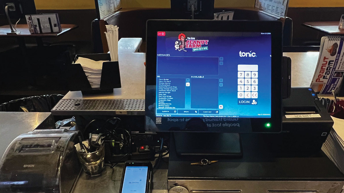 A touch-screen POS terminal running Tonic software displays the login screen for "The New Peanut Farm Sports Bar & Grill" at a counter.