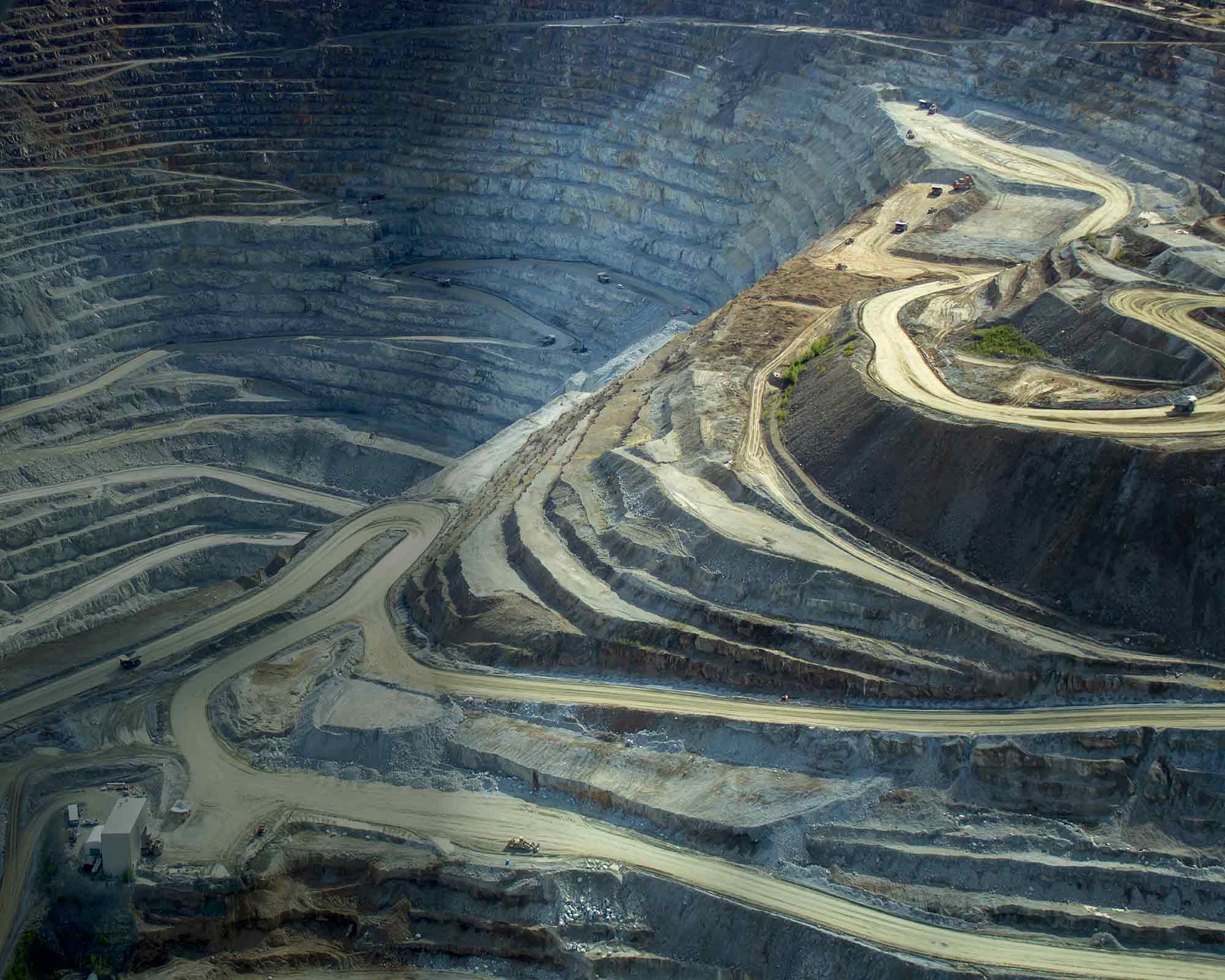 An aerial view of a massive, deep open-pit mine with terraced, winding roads.