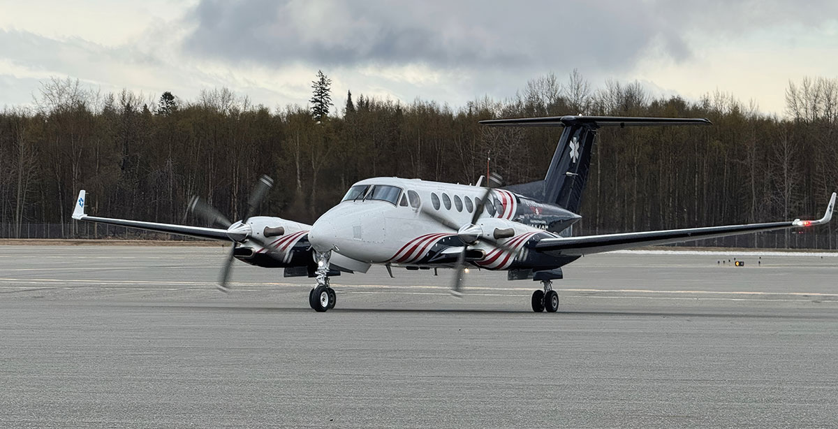 A twin-turboprop air ambulance plane taxiing on an airfield runway