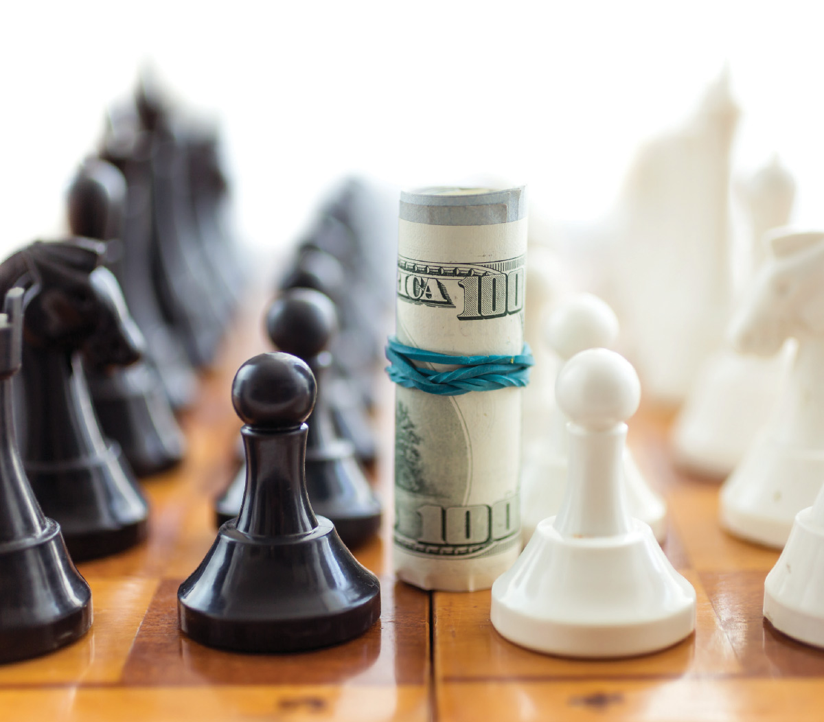 A rolled-up stack of 100-dollar bills stands between black and white pawns on a wooden chessboard.
