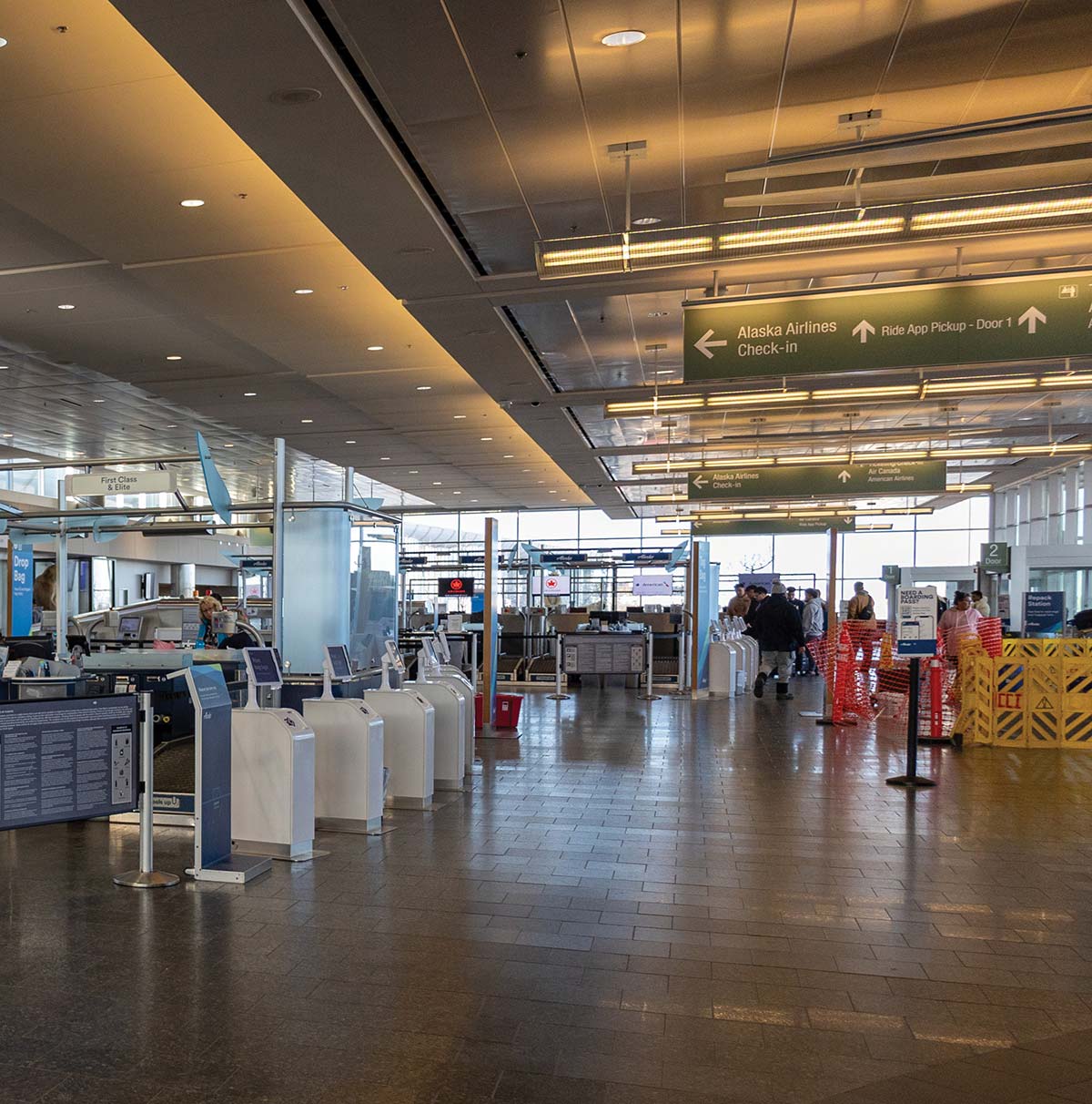 An indoor view of a spacious airport terminal check-in area with informational signs overhead.
