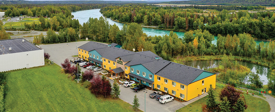 Aerial view of a yellow and teal hotel next to a winding river.