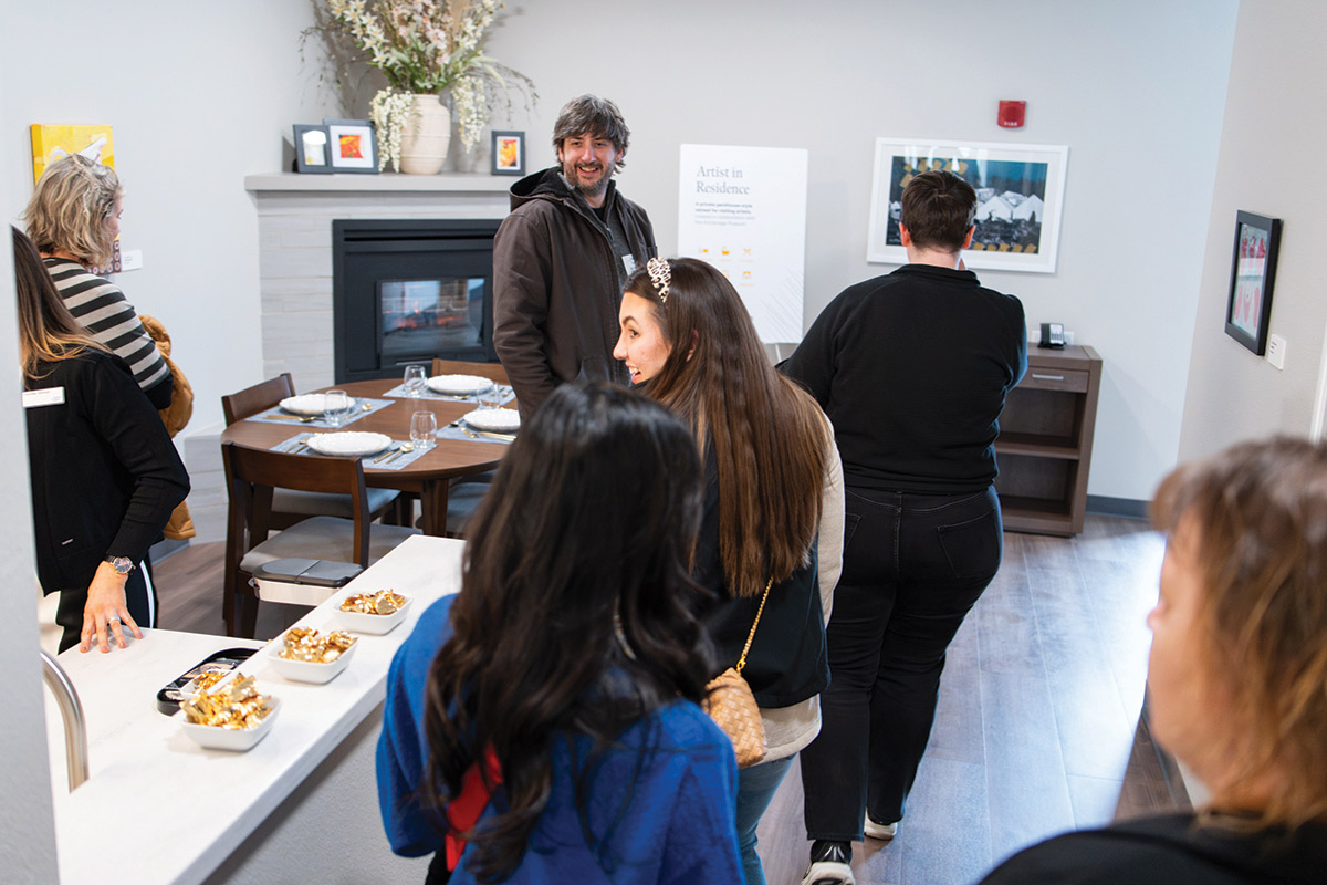 A group of people gathers in a dining area near a fireplace.