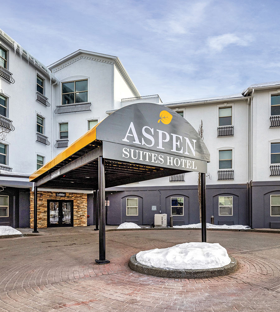 The entrance of the Aspen Suites Hotel with a covered driveway and snow.