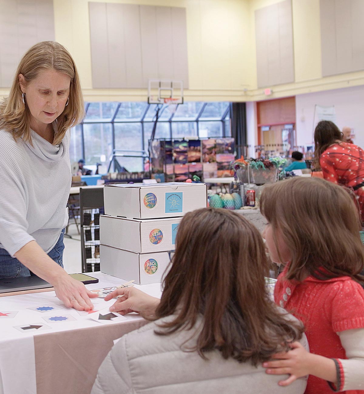 A woman demonstrating educational materials to a parent and child at an activity booth.
