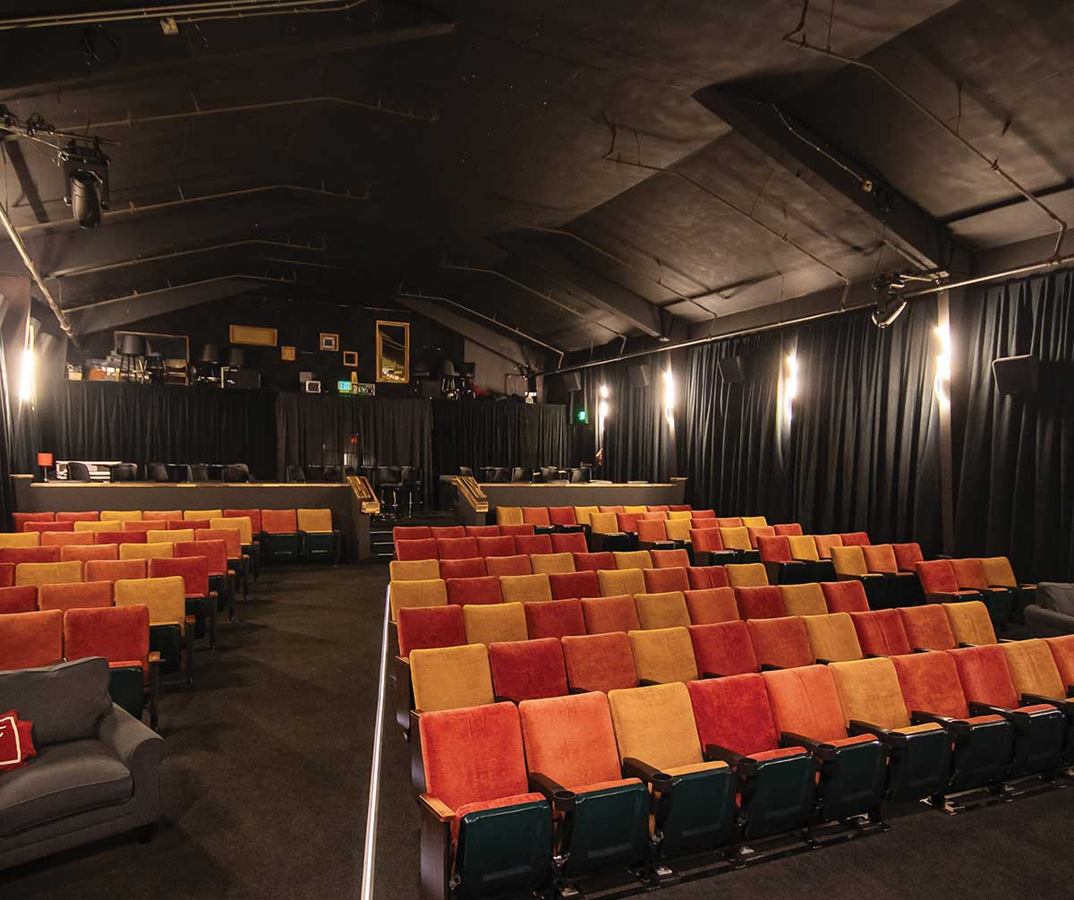 An interior view of a theater seating area filled with warm-colored chairs facing forward.