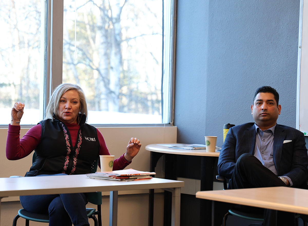 Woman gesturing during a meeting while a man in a suit listens beside her.