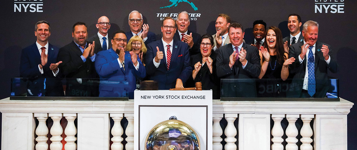 Executives clapping and celebrating at the podium during a New York Stock Exchange event.