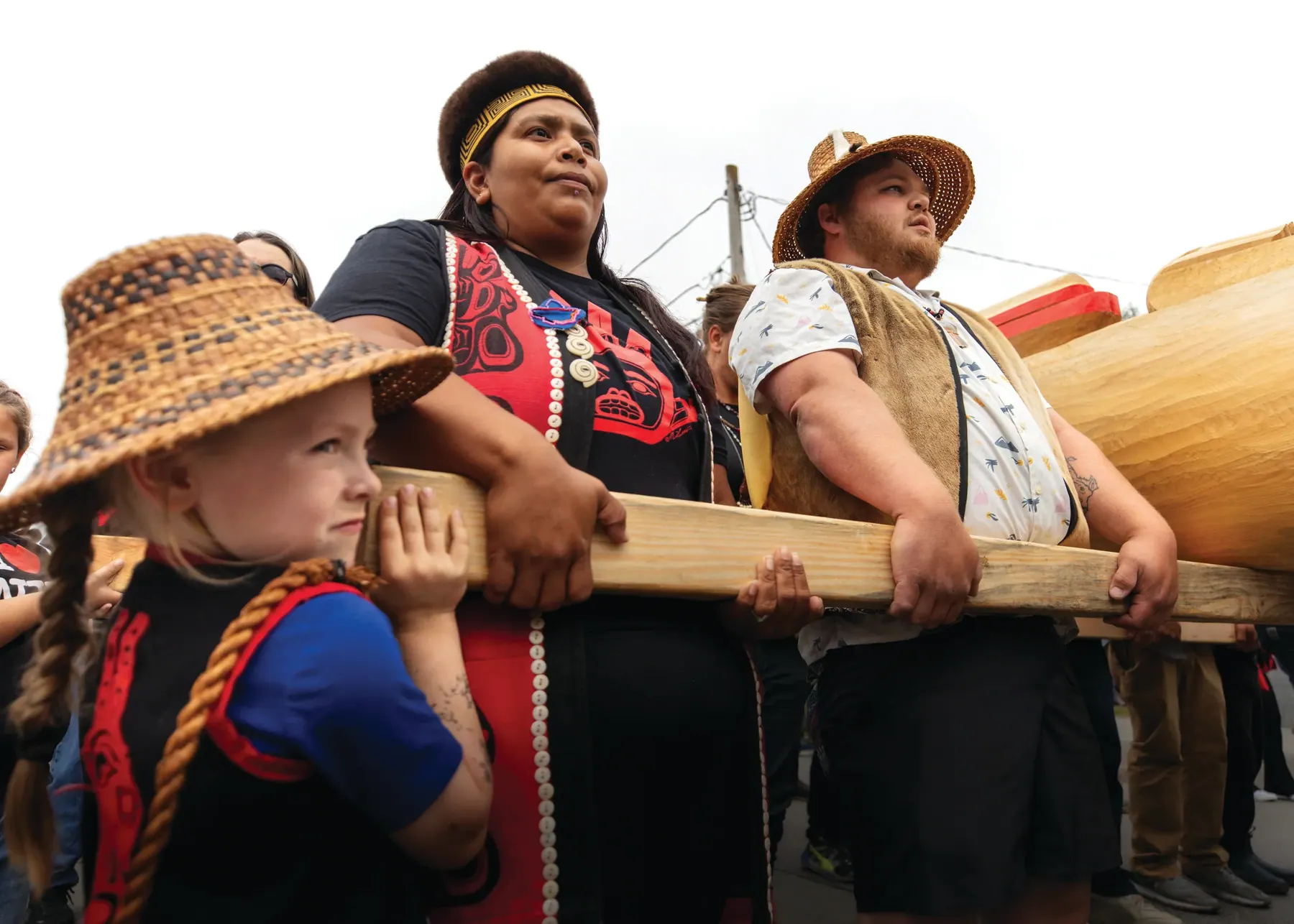 Bamby James and Brandon Ware, with assistance from Jaxon Shilts, carry the Kadashan Totem Pole.